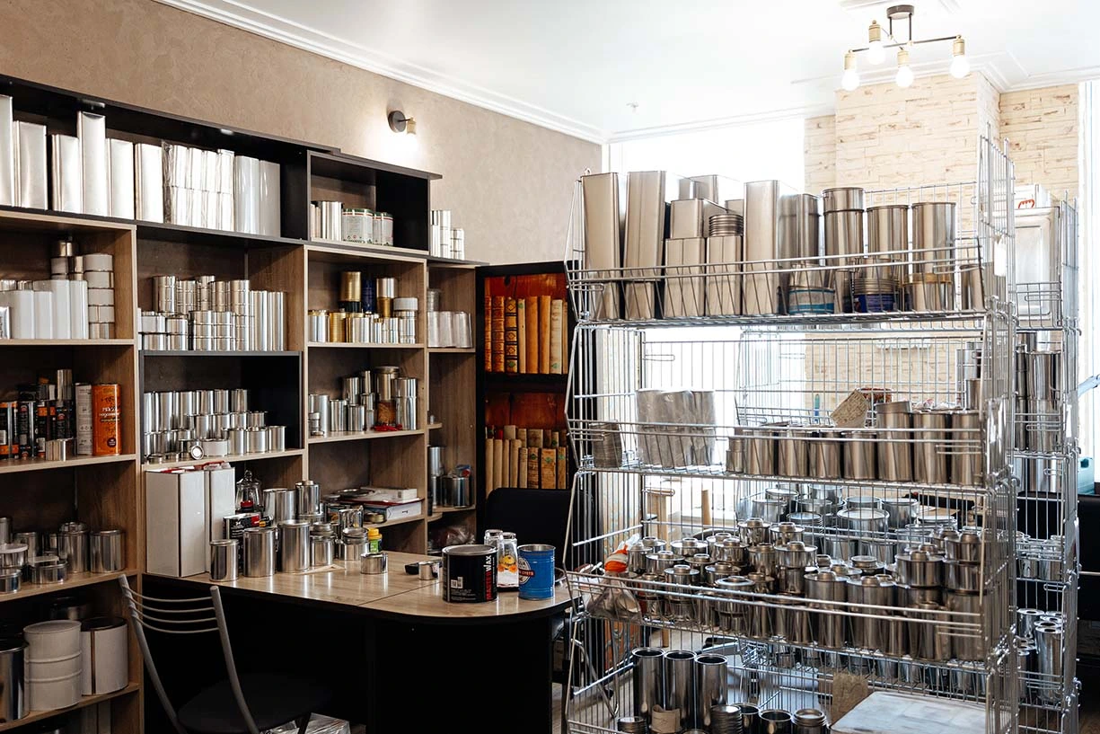 Образцы жестяных банок и металлической тары производства завода Тармет Образци готовой продукции завода Тармет: жестяные банки оптом, металлические контейнеры и тубусы различных диаметров на стеллажах.